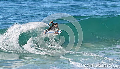 Skim Boarder riding a shore break wave at Aliso Beach in Laguna Beach, California. Editorial Stock Photo