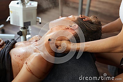Skin Care. Beautician Applying Brown Face Mask During Beauty Treatment For Relaxed Woman. Stock Photo