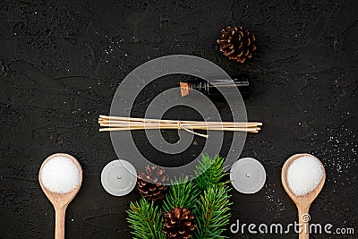 Skin care and relax. Cosmetics and aromatherapy concept. Pine spa salt, oil, spruce branch and pinecones on black Stock Photo