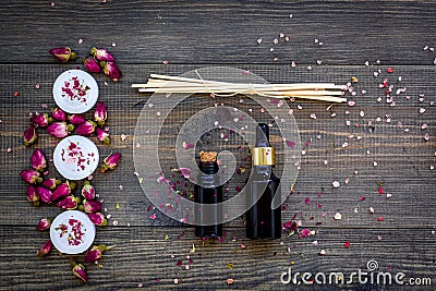 Skin care and relax. Cosmetics and aromatherapy concept. Rose oil and candles on dark wooden background top view Stock Photo