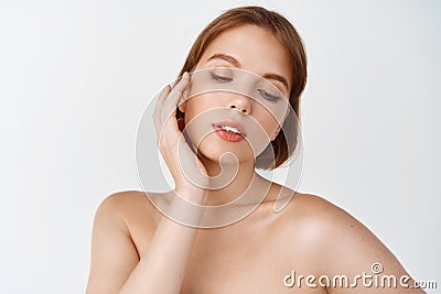 Skin care and women beauty. Gentle young woman naked shoulders, touching natural facial skin without makeup, apply daily Stock Photo