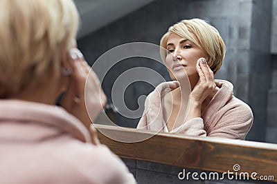 Skincare Routine. Anti Aging Beauty Treatment Concept. Mature Woman Cleans Face Skin With Cotton Pads. Stock Photo