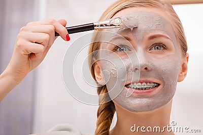 Woman applying with brush clay mud mask to her face Stock Photo