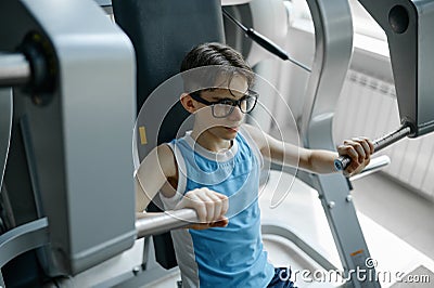 Skinny preteen nerd trying to be strong and healthy training at gym Stock Photo