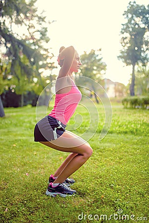 Skinny woman in park, doing squats and running at sunset Stock Photo