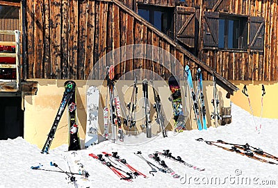 Skis and snowboards on the snow against alpine chalet Editorial Stock Photo