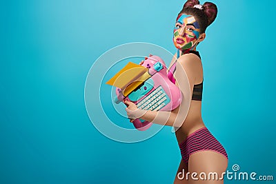 Skittish model holding pink toy typewriter. Stock Photo