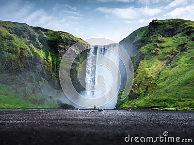 Skogafoss waterfall, Iceland. Mountain valley and clear sky. Natural landscape in summer season. Icelandic nature. Group of a peop Stock Photo