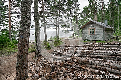 Skuleskogen, Sweden - 08.22.2021: Wooden cabin in the forest of Skuleskogen national park in Sweden with pile of birch Stock Photo