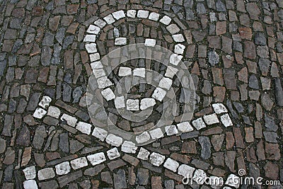 Skull and bones made with white stones in the cobblestone road. Stock Photo