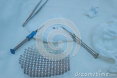 Neurosurgical instruments, including a titanium plate for implantation in the skull, are on the sterile operating table of a nurse Stock Photo