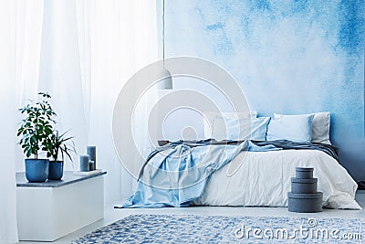 Sky blue bedroom interior with double bed, plants and grey boxes Stock Photo