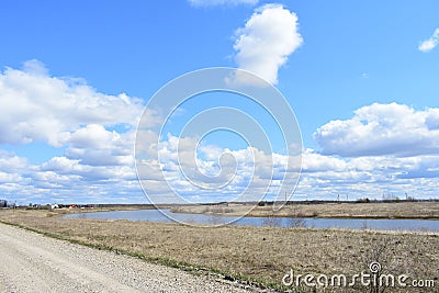 Sky, clouds. Road. Village on the banks of the river. Fields of young grass. Agricultural Stock Photo