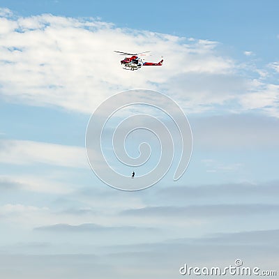 Sky with a person hanging by a rope on a chopper Stock Photo