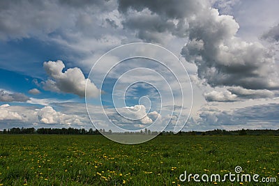 Cloudy sky over a meadow with dandelions. Stock Photo