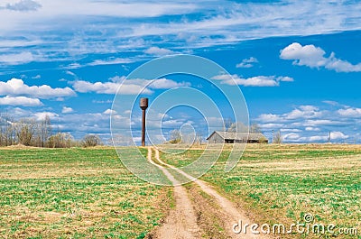 Sky road in the field leading to the shed barn and water tower of the rural landscape of the village. Stock Photo