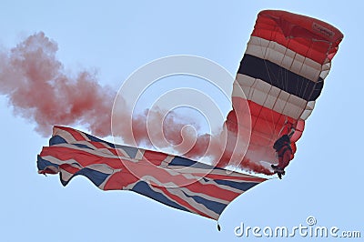 Skydiver descends to the ground trailing bright red smoke and flying the British Union Jack flag Editorial Stock Photo