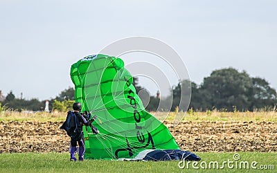 A skydiver gathering up his green chute Editorial Stock Photo