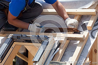 Skylight installation. Roofer builder worker use saw to cut a wooden beam. Stock Photo