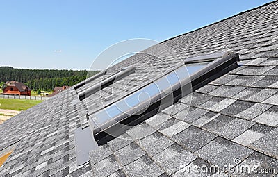 Skylights windows on modern house roof top. Attic skylight windows on asphalt shingles roof Stock Photo