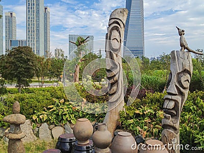 Skyline of Songdo in South Korea, wooden totem poles called jangseung in a park Stock Photo