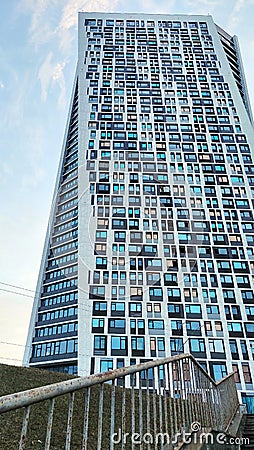 A skyscraper of a futuristic shape against a blue sky. An example of modern architecture. Many windows are repeated in a pattern Editorial Stock Photo