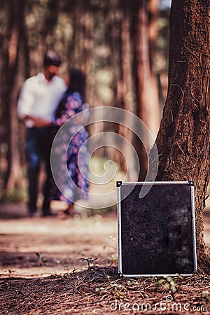 Slate in focus with couple standing in the background surrounded by trees Stock Photo
