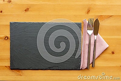 Slate place mat with fish knife and fork on top of a folded napkin Stock Photo