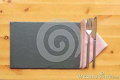 Slate place mat with knife and fork on top of a folded napkin Stock Photo
