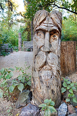 An ancient wooden statue of an idol carved from a solid tree trunk. Public object Editorial Stock Photo