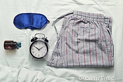 Sleep mask, sleeping pills, alarm clock and pajamas Stock Photo