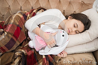 Sleep with toy. Girl enjoy evening time with favorite toy. Kid lay bed and hug bunny toy couch pillow blanket background Stock Photo