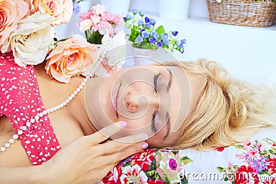 Sleeping blond woman lying on pillow among flowers Stock Photo