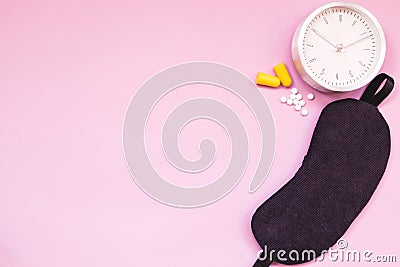 Sleeping eye mask, alarm clock, ear plugs and sleeping pills or vitamins on colourful background. Stock Photo