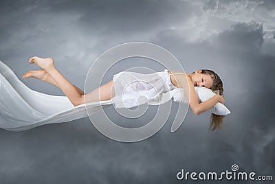 Sleeping girl. Flying in a dream. Clouds on grey background. Stock Photo