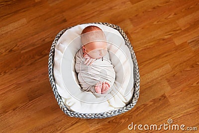 Sleeping newborn baby in a basket. Small hands and feet of the child. Baby wrap Stock Photo