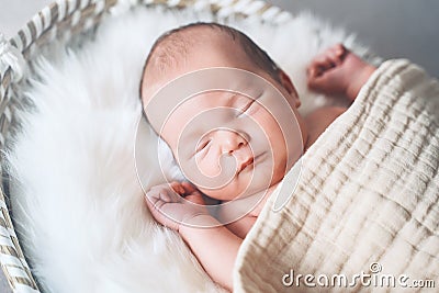 Sleeping newborn baby in basket wrapped in blanket in white fur background. Portrait of little child one week old Stock Photo