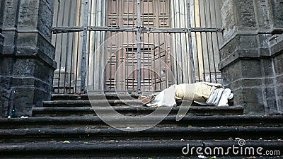 Sleeping rough homeless on the stairs of the building in front of the gate Stock Photo