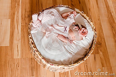 Sleeping two-week-old baby girl in golf course and pink dress sleeps on white plaid Stock Photo