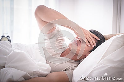 Sleepless hangover man on bed up with headache Stock Photo