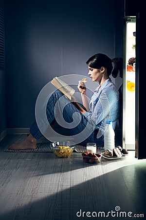 Sleepless woman reading in the kitchen Stock Photo
