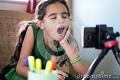 Sleepy boredom kid yawning during online class infront of mobilephone - concept of tired or bored child during Stock Photo