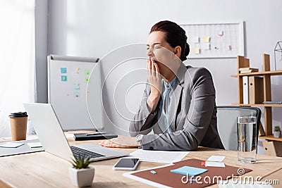 Sleepy businesswoman with hand near mouth Stock Photo