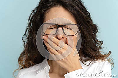 Sleepy employee office woman wear glasses bored, yawn with closed eyes, covers mouth with hand Stock Photo
