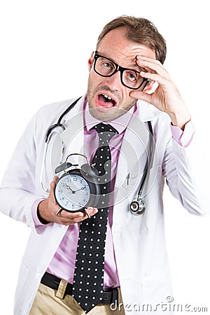 Sleepy, exhausted male doctor wearing glasses holding an alarm clock, tired after a busy da Stock Photo