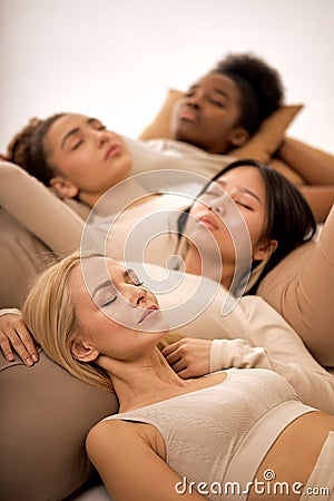 sleepy young diverse ladies lying on floor in studio, calm and pacified, isolated Stock Photo