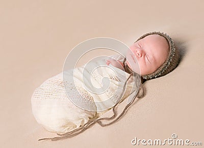 Sleepy swaddled newborn baby in knitted hat Stock Photo