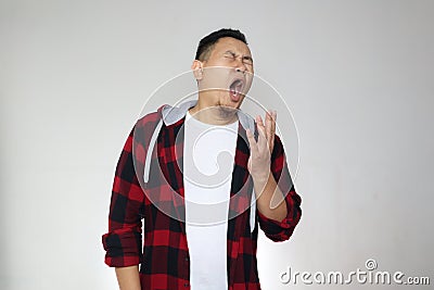 Sleepy tired funny young Asian man yawning, half body portrait over grey Stock Photo