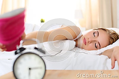 Sleepy young beautiful woman trying kill alarm clock Stock Photo