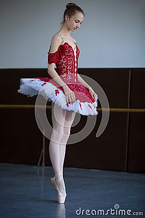 Slender ballerina standing on pointe in the ballroom looking down Stock Photo